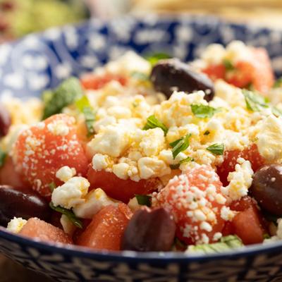 Watermelon Salad topped with crumbled feta cheese and hebs, close-up.