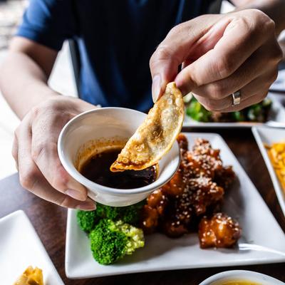 Hand dipping a dumpling into a cup of soy sayce.