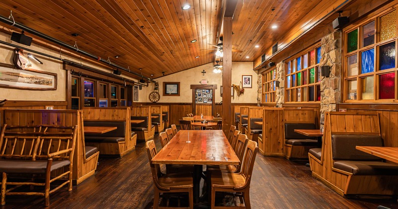 Restaurant interior with wooden tables, booths, and colorful stained glass windows