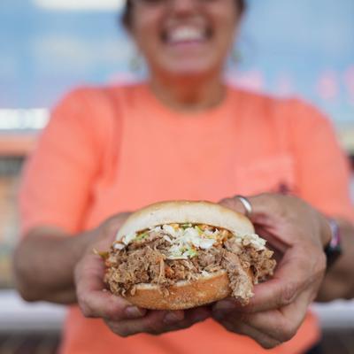 staff member holding minced barbecue sandwich.