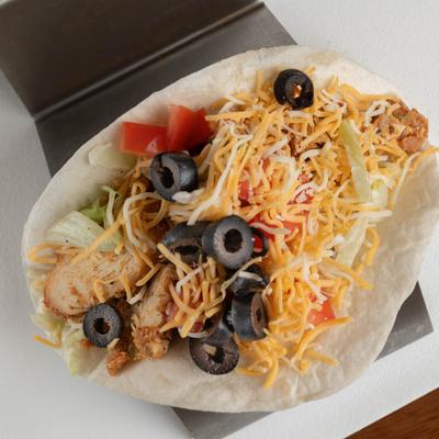 Grilled chicken taco, with lettuce, tomato, black olives, and shredded cheese.