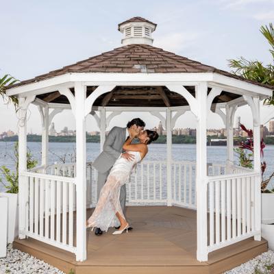 Couple embracing inside a white waterfront gazebo.