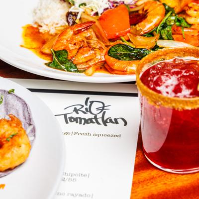 Cocktail served on the table with a menu and Tequila Shrimp with rice.