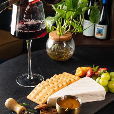 Brie cheese with crackers, fruit, dried figs, and a glass of red wine.