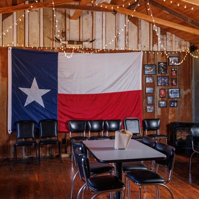 Rustic style interior design, seating area with a large Texas flag on a wall and string lights.