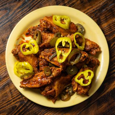 Plate of wings topped with sliced hot peppers.