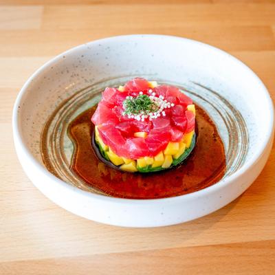 Tuna tartare with diced mango and avocado, served in a bowl with sauce.