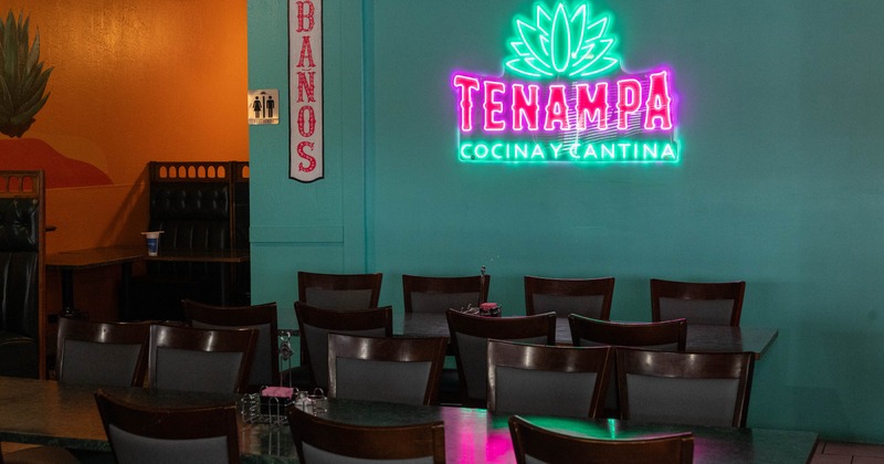 Restaurant interior with dark wooden chairs and neon sign on the wall