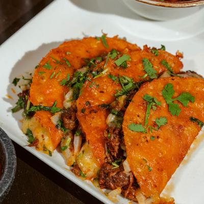 Birria tacos garnished with fresh herbs.