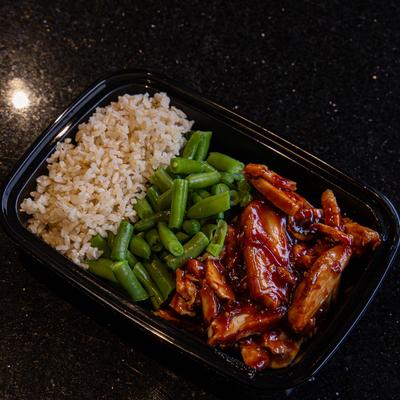 Grilled sliced meat with sauce, rice and green vegetables on the side