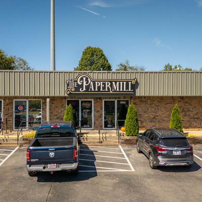 Storefront with signage and a parking lot with parked cars.