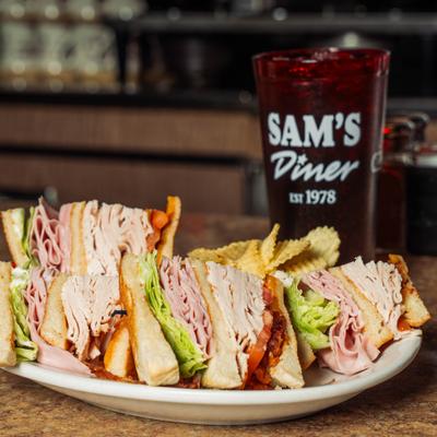 Club sandwich with potato chips and iced drink.