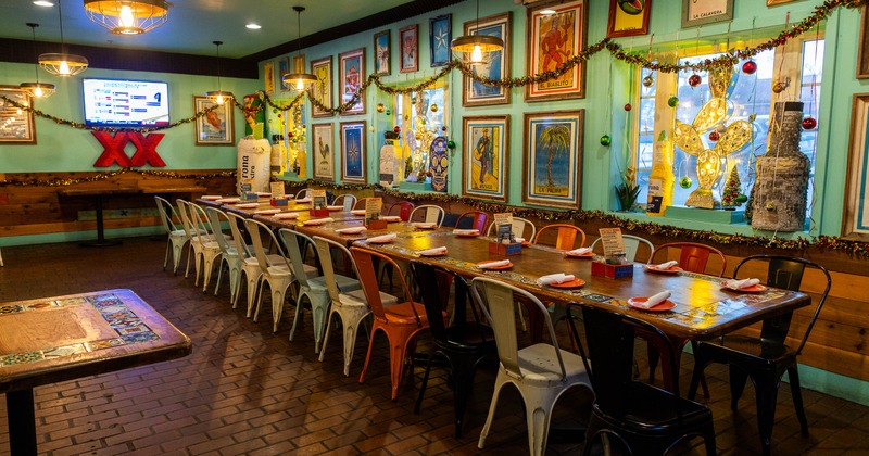 Interior with a long dining table, metal chairs, green walls with colorful pictures