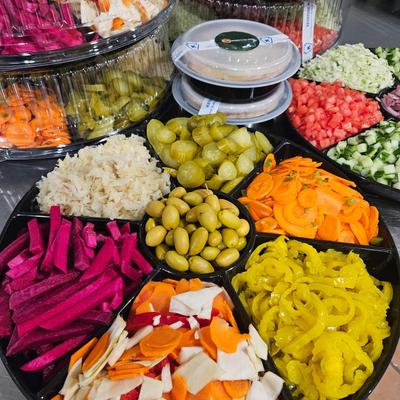 Multiple catering platters featuring a variety of pickled vegetables and olives.