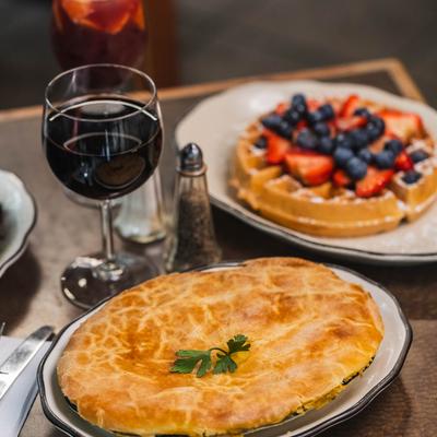 Chicken pot pie on a table with red wine, sangria, and waffle topped with berries.
