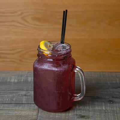 A refreshing purple drink with ice, garnished with a lemon slice.