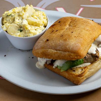 Kimberlina sandwich with chicken, bacon, avocado, Swiss cheese and side of potato salad.