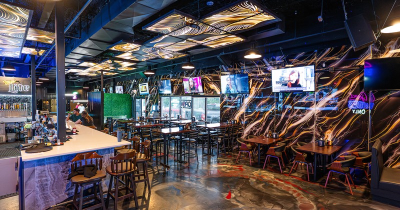 Interior of modern sports bar with a long bar and dining tables and chairs