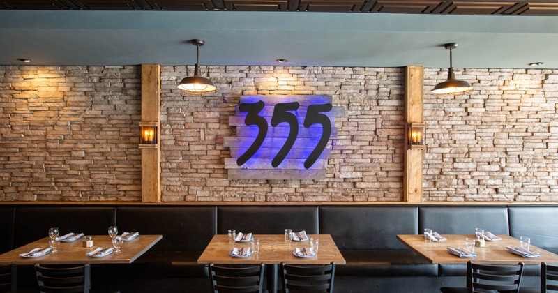 Interior, long leather padded banquette bench, tables and chairs, logo on the wall