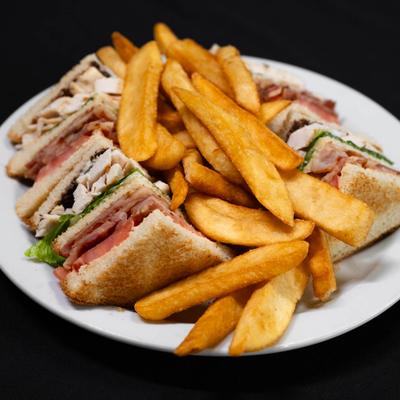 A delicious club sandwich served with fresh french fries..
