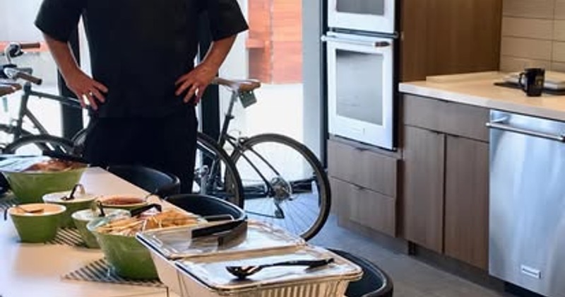 Person standing in a modern kitchen next to a bicycle and a counter