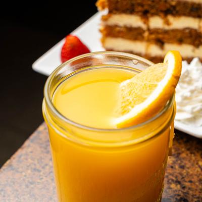 Glass of orange juice garnished with a slice of orange.