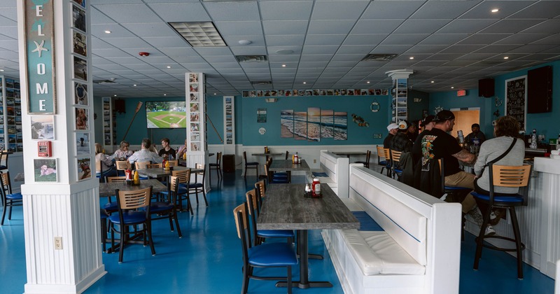 Restaurant interior with blue flooring, ocean artwork, and seated guests