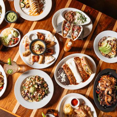 Assorted food plates and drinks arranged on a table, overhead view.