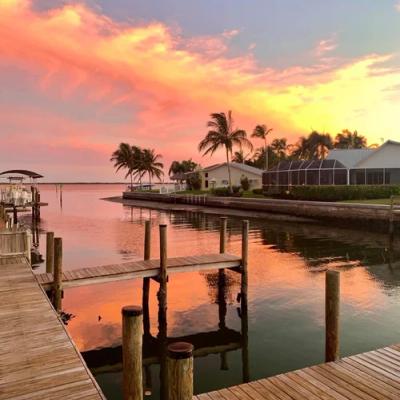 Waterfront sunset scene with docks, buildings and palm threes.
