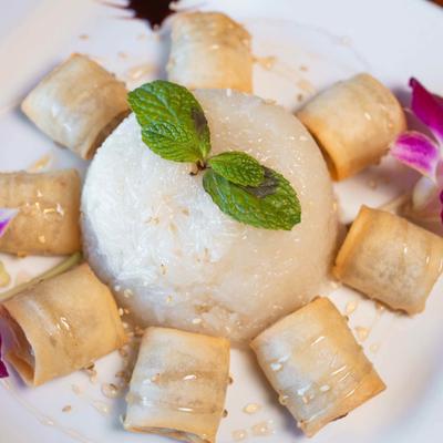 Fried banana slices with sweet rice, honey drizzle, and mint garnish.