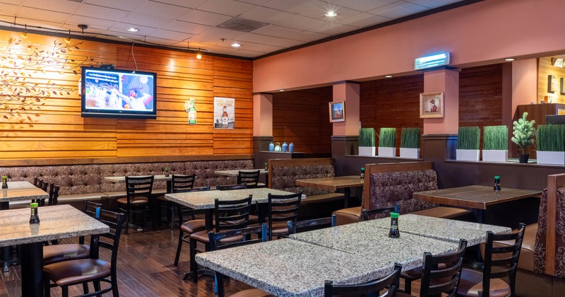 Interior with granite tables, wooden chairs, a TV and decorative plants