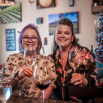 Two people smiling while holding wine glasses.