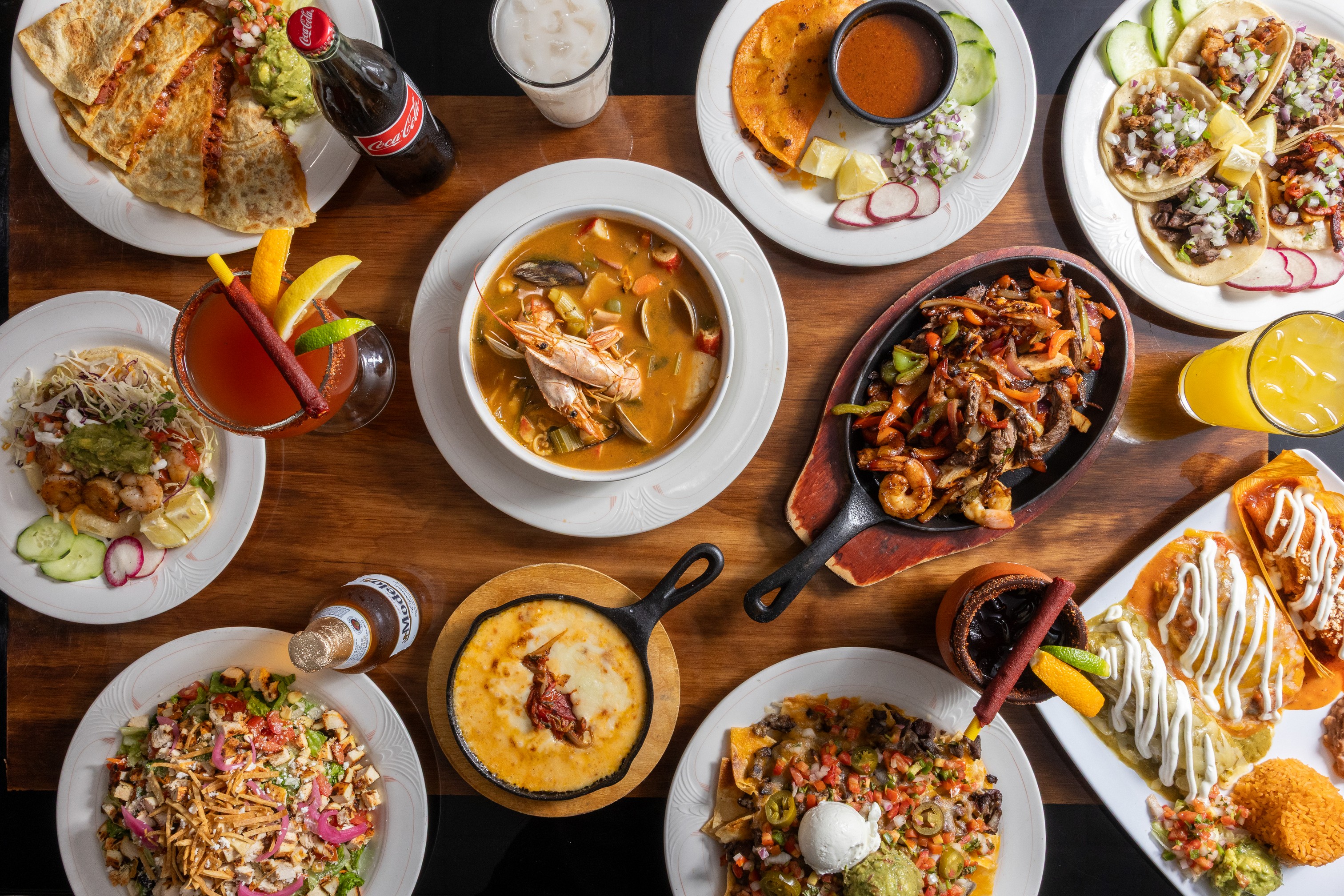 Assorted Mexican dishes and drinks spread across a table