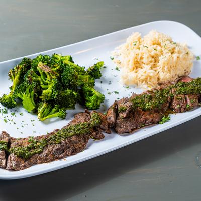 Grilled skirt steak with chimichurri sauce, served with rice and steamed broccoli.