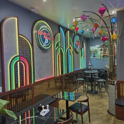 Interior, seating area with modern decor, neon lighting and colorful lanterns.