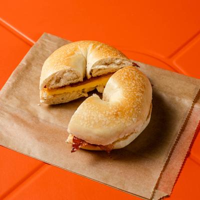 Breakfast sandwich featuring a sliced bagel filled with egg, cheese and bacon.