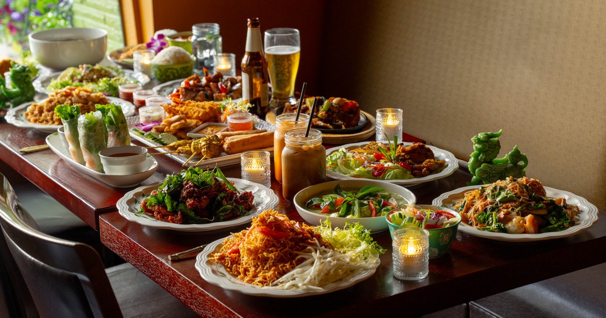 Table with a variety of Asian dishes and drinks with candles and dragon figurines.