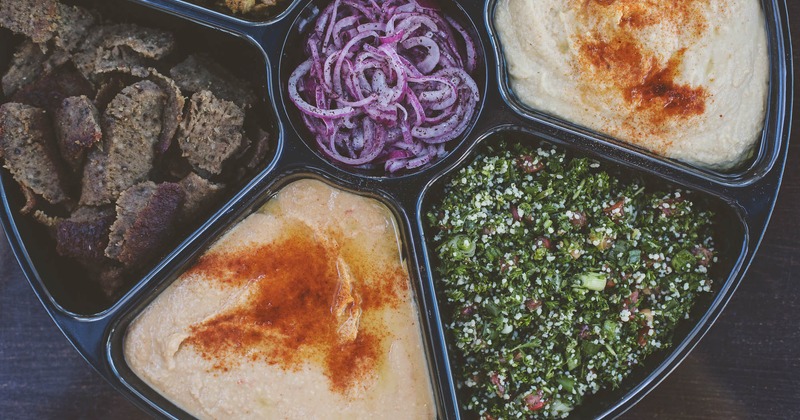 Catering platter with gyro meats, quinoa salad, hummus, and red onion
