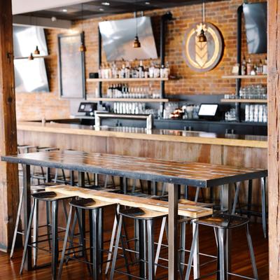 Industrial-style bar interior with high-top seating and exposed brick walls.