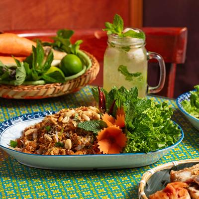 Nam Kow Tod with a lychee-mint lemonade and other food on a table.