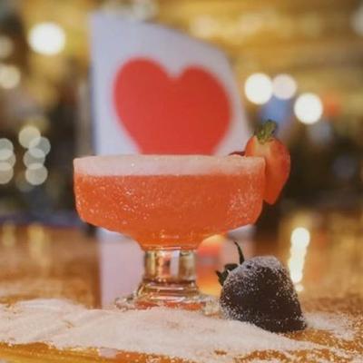 A small glass of cocktail with a slice of strawberry