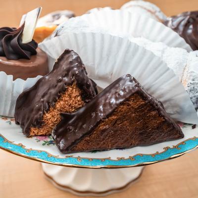 Assorted chocolate-covered pastries and cakes on a decorative tiered plate.
