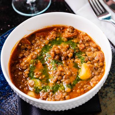 Bowl of lentil soup drizzled with green herb oil.