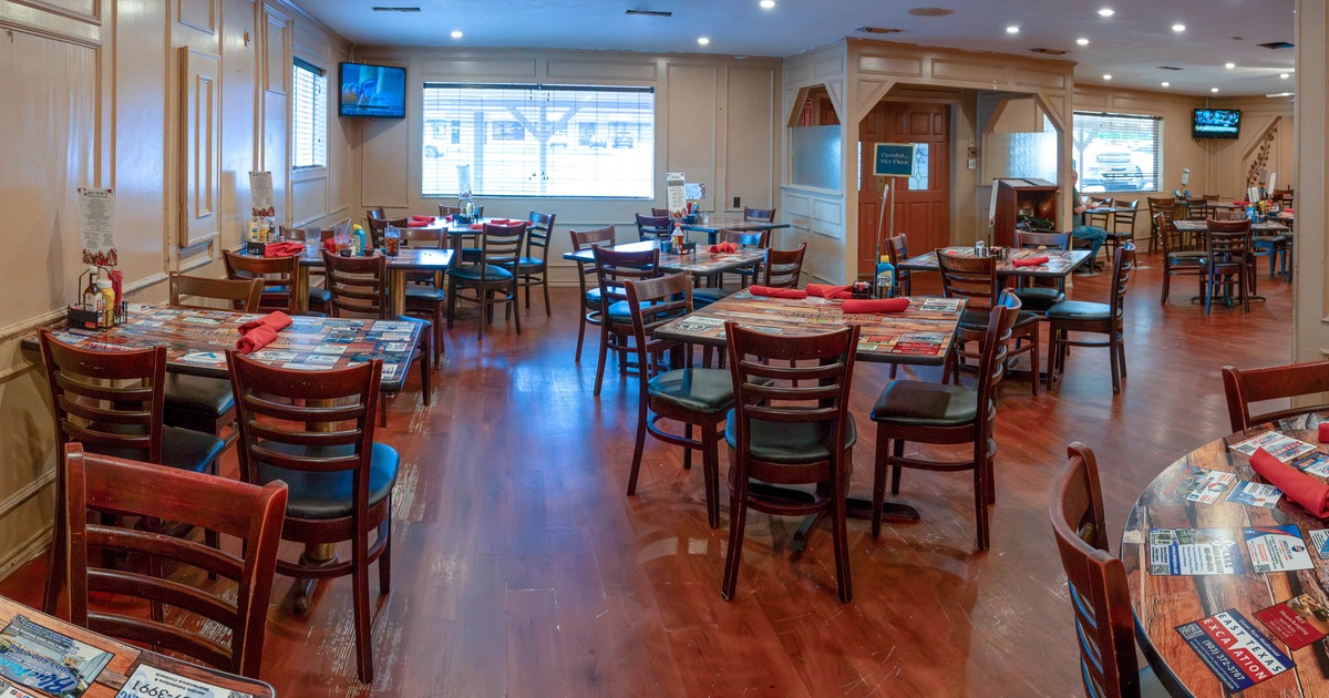 A restaurant interior with wooden tables, red napkins, and decorative paneling