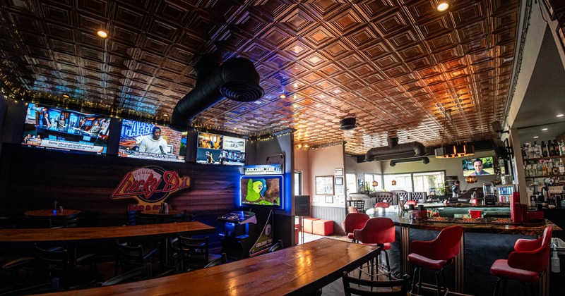 Interior, seating area, high wooden top tables, regular tables, bar on the right, TVs on the wall