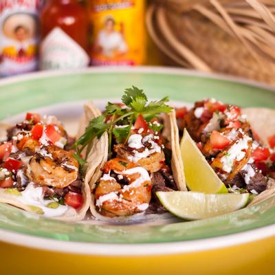 Tacos with grilled shrimp and steak, guacamole, salsa, cream and cheese