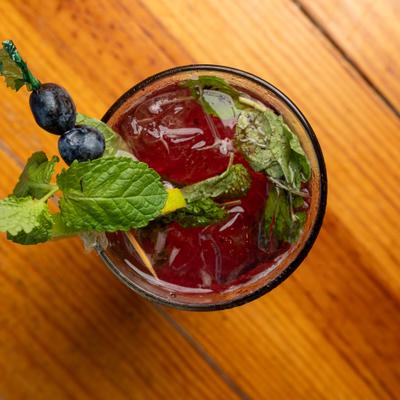 Tall Blueberry Cocktail, garnished with blueberries, fresh mint and a lemon slice.