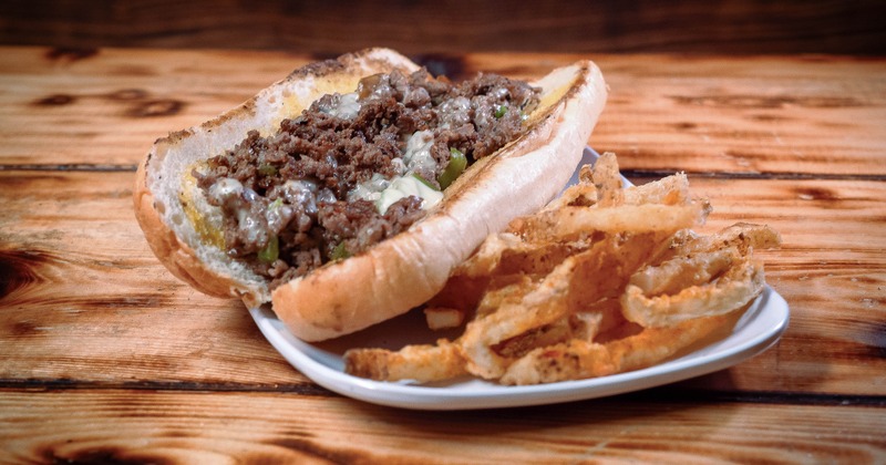 A cheesesteak sandwich filled with beef and cheese, served with crispy french fries