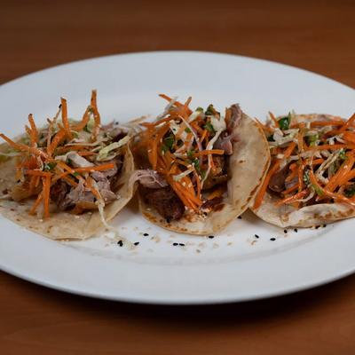 Duck carnitas tacos topped with a shredded carrot and cabbage slaw.