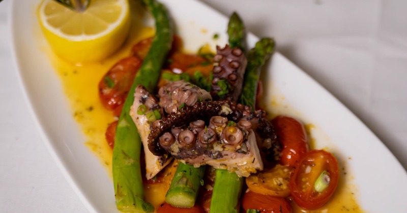 Three beef patties topped with microgreens, served next to two sauce dips